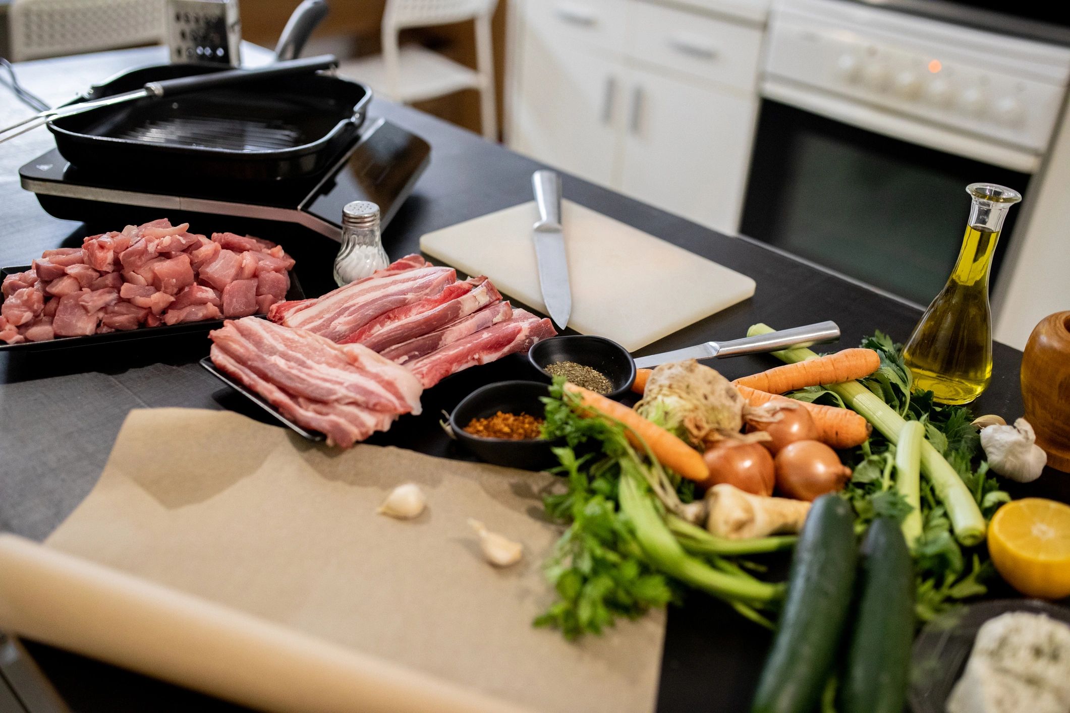 Pieces of raw pork and beef on a cutting board with vegetables